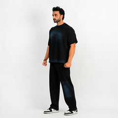 Man wearing a black outfit with blue splatter design on a white background