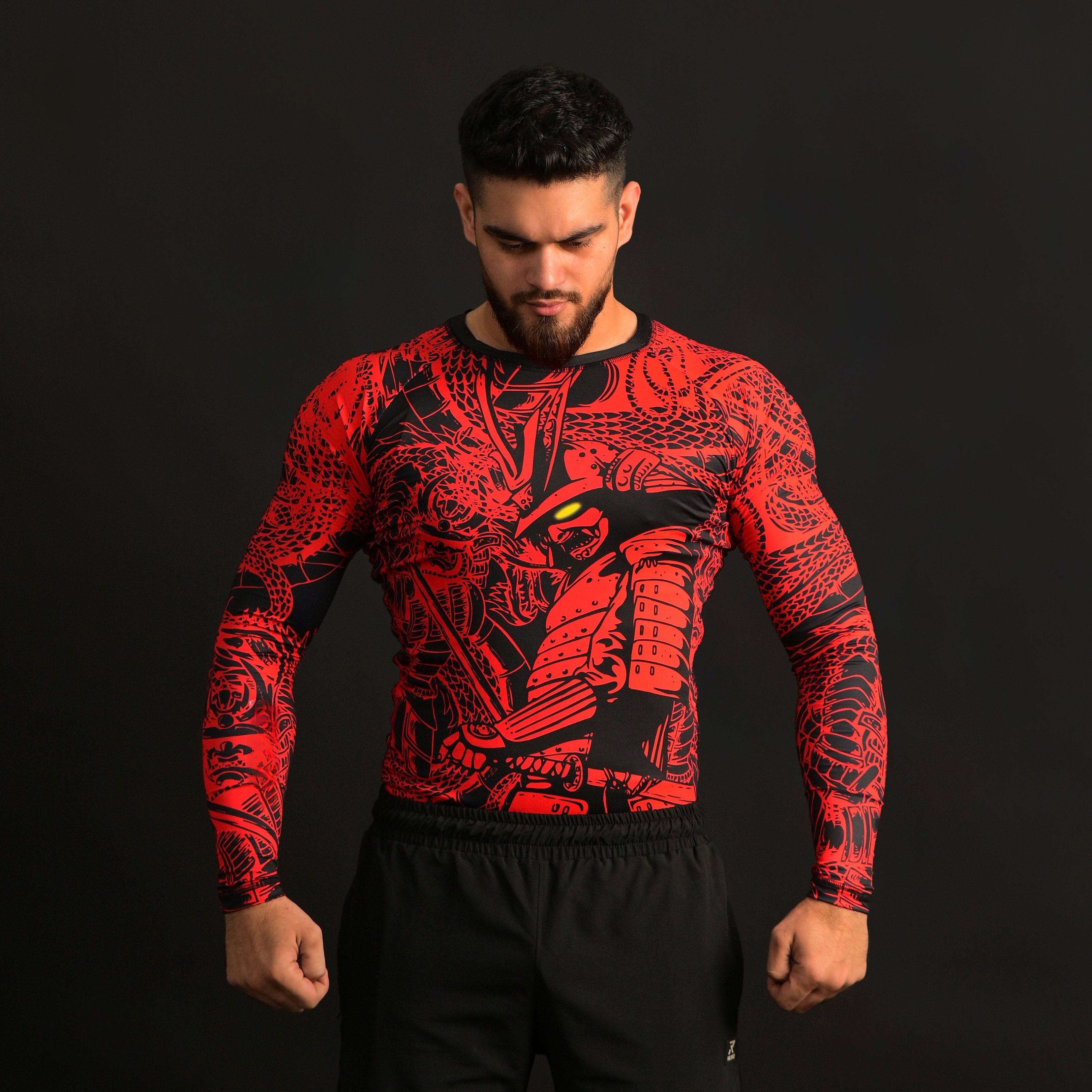Man wearing a red and black patterned long-sleeve shirt on a black background