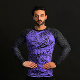 Man wearing a purple and black patterned long-sleeve shirt against a black background
