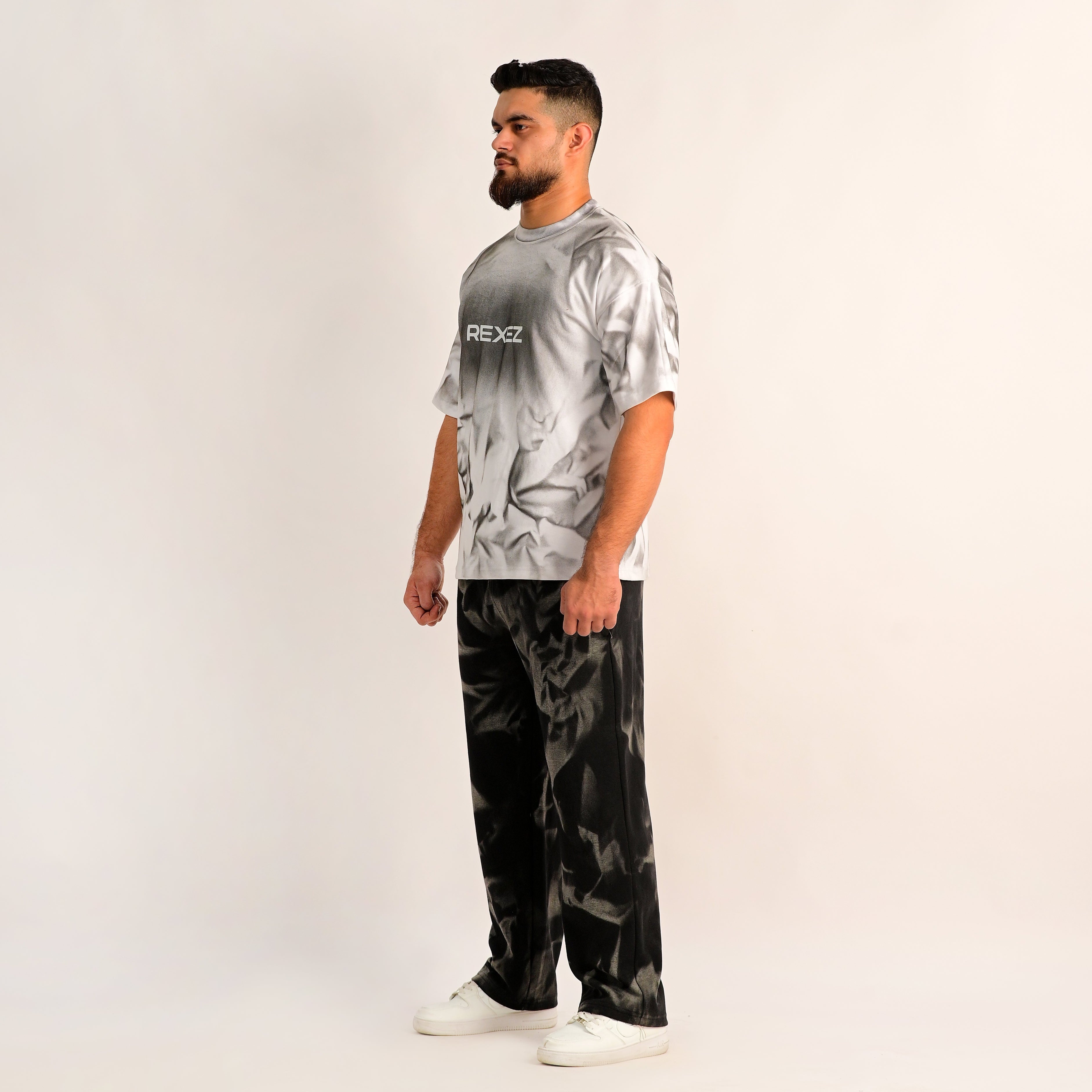 Man wearing a tie-dye shirt and camouflage pants on a white background