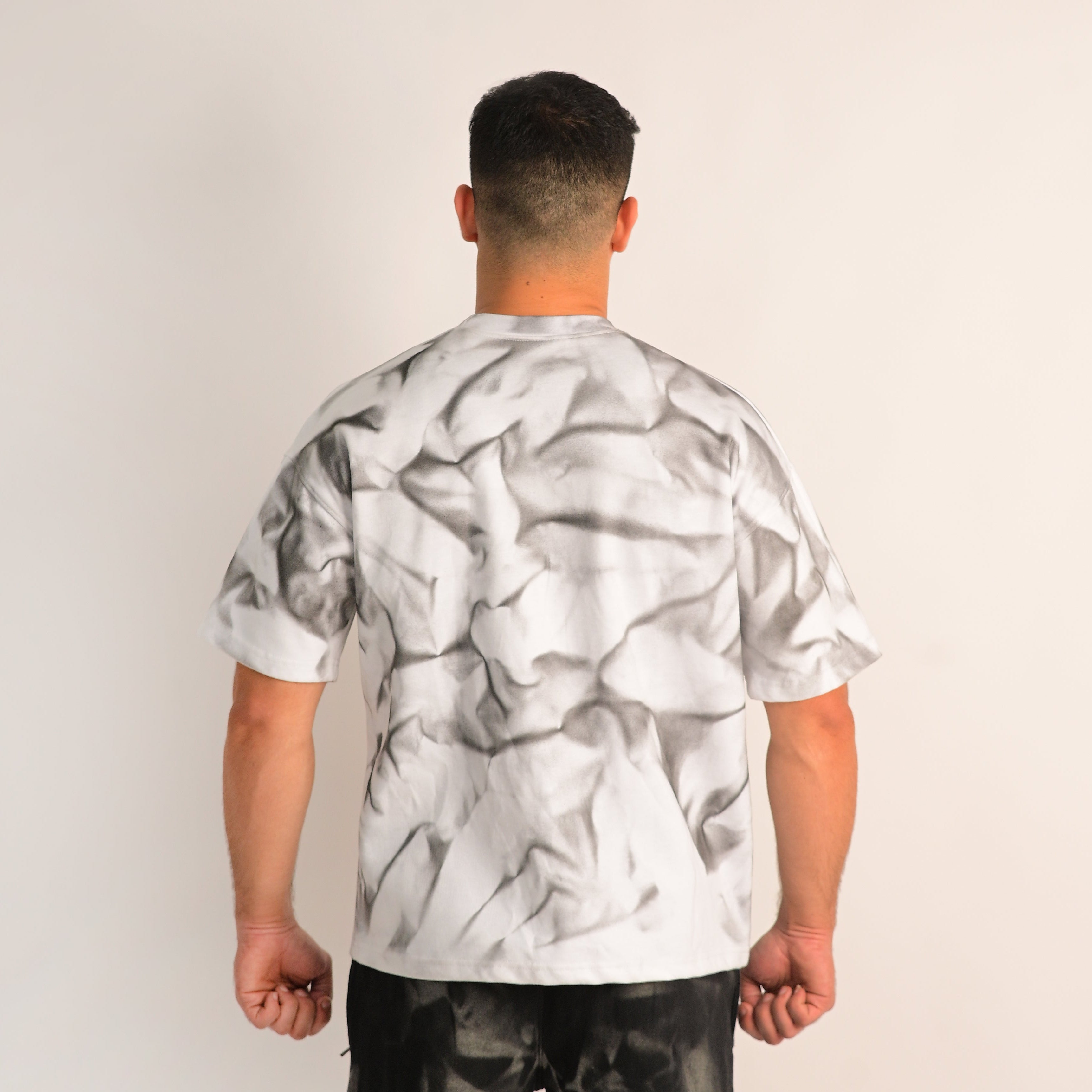 Person wearing a white t-shirt with black abstract pattern on a plain background
