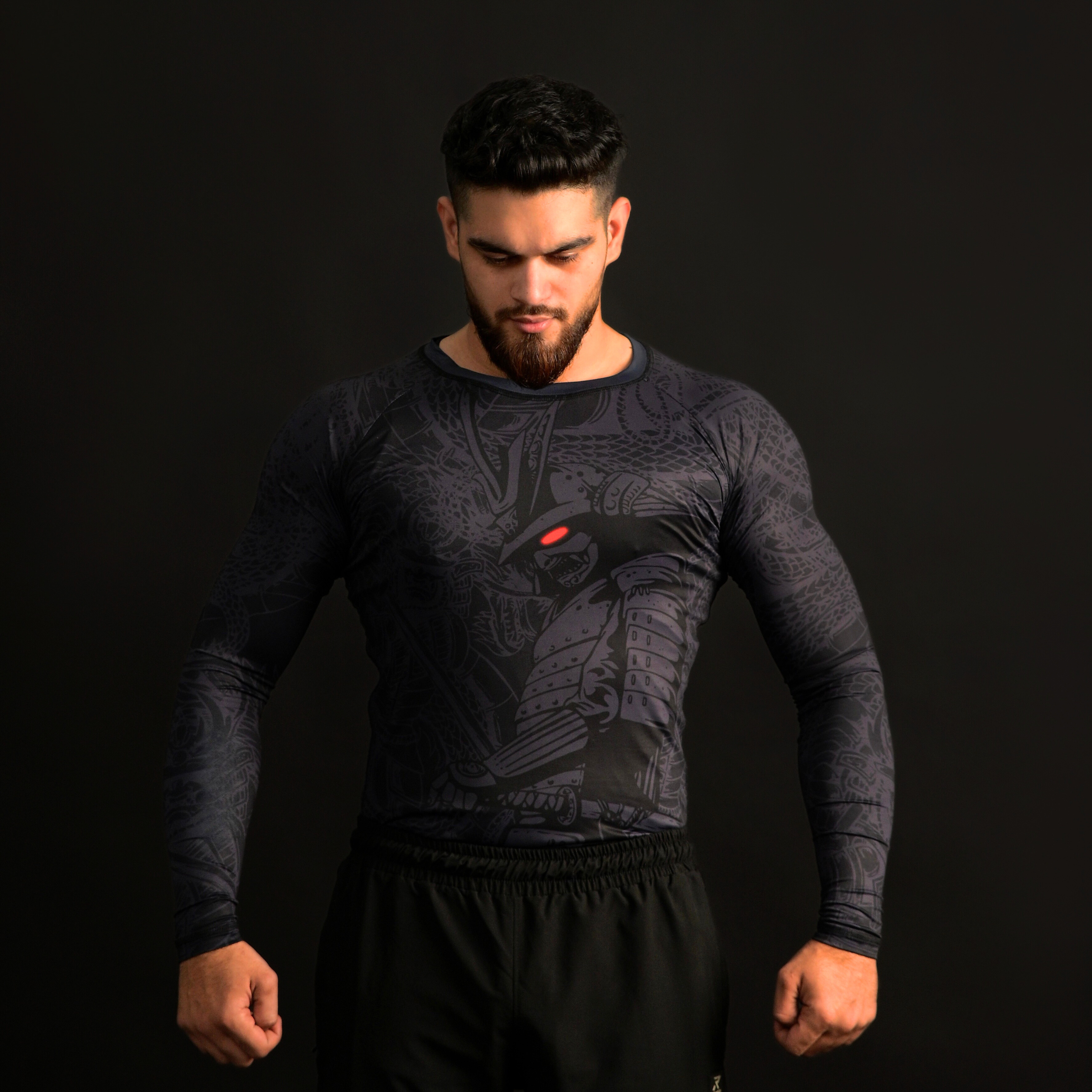 Man wearing a black athletic shirt with a design on a dark background