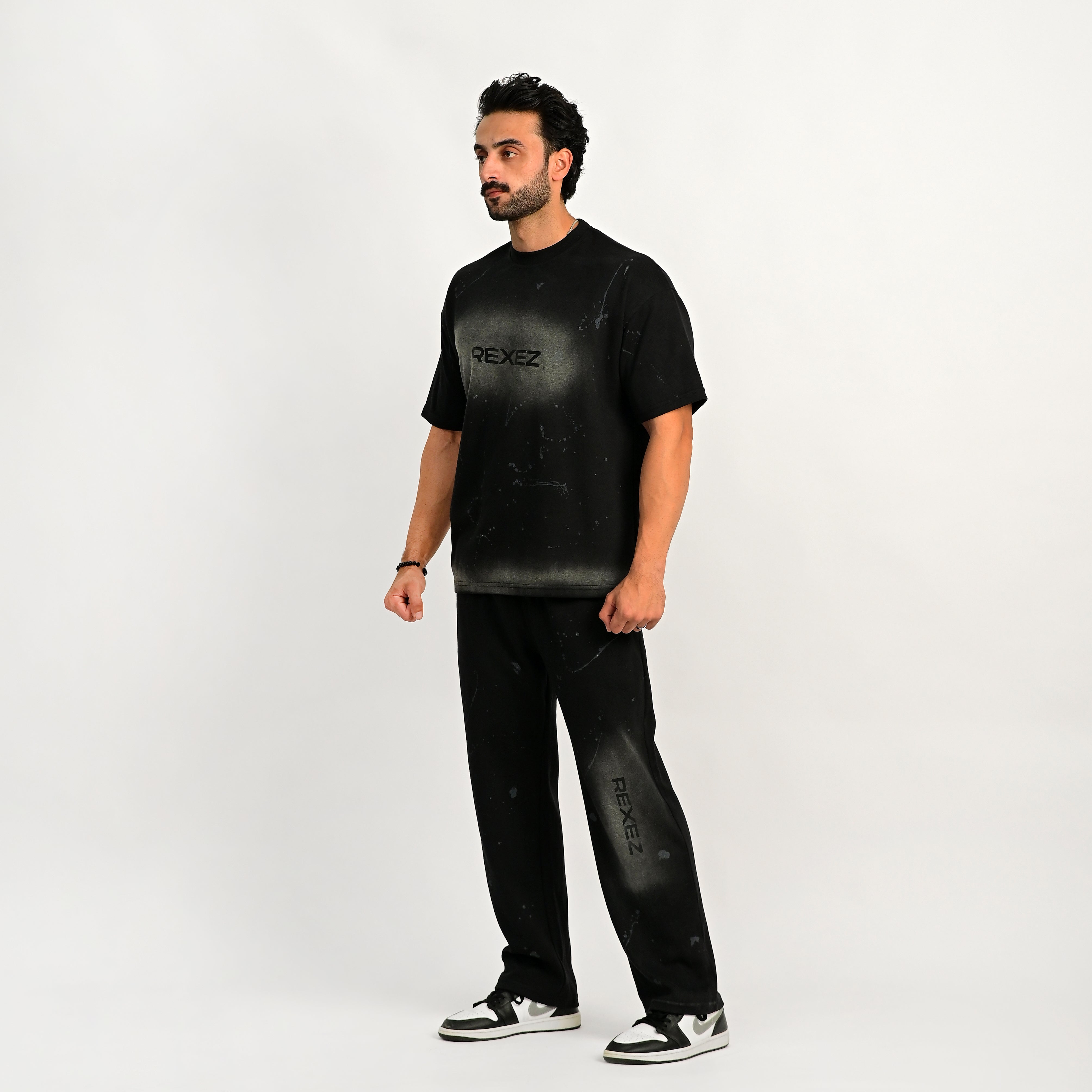 Man wearing a black t-shirt and pants with 'REXEZ' branding on a white background