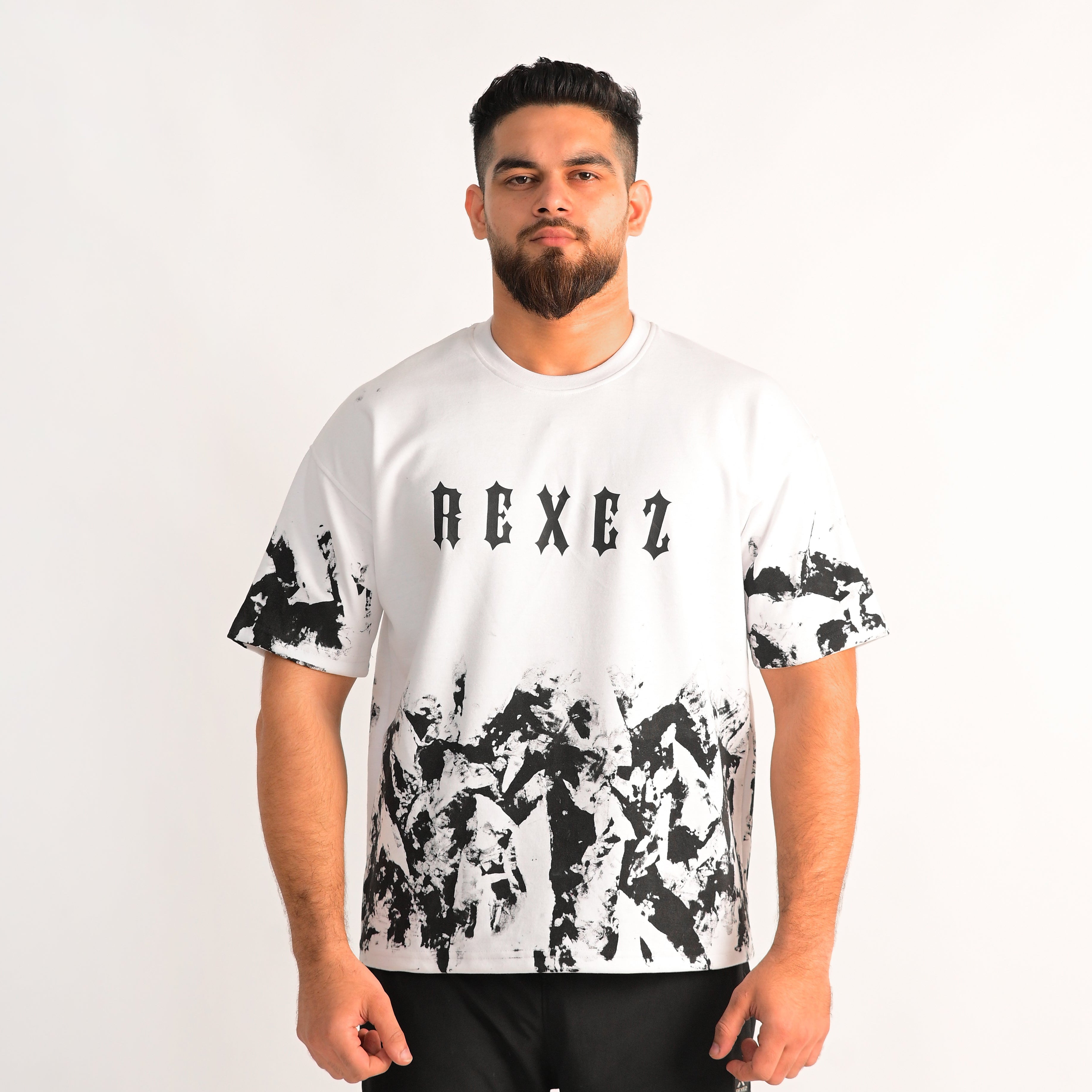 Man wearing a white t-shirt with black abstract patterns and 'REXEZ' branding on a plain background