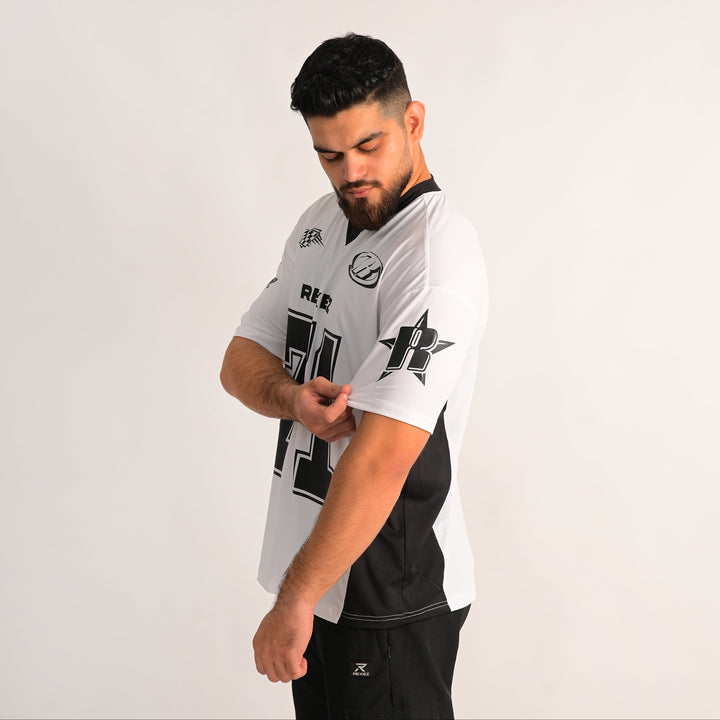 A man wearing a white and black athletic jersey with sponsor logos, posing against a plain light gray background.
