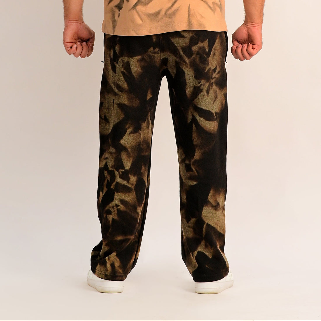 Man wearing a beige shirt and camouflage pants on a white background