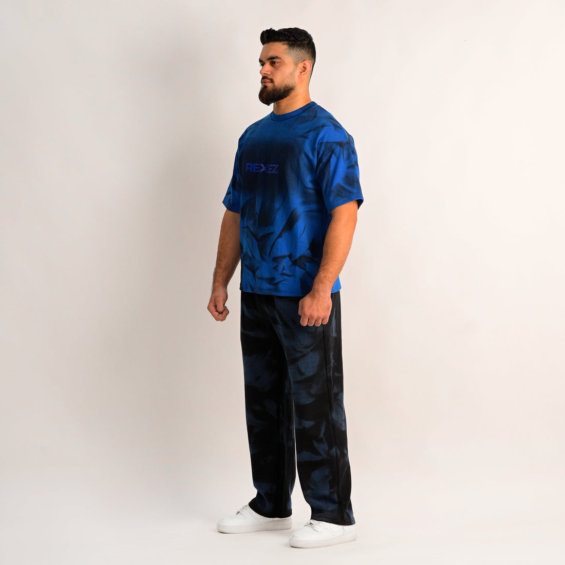 Man wearing a blue and black patterned outfit on a plain background