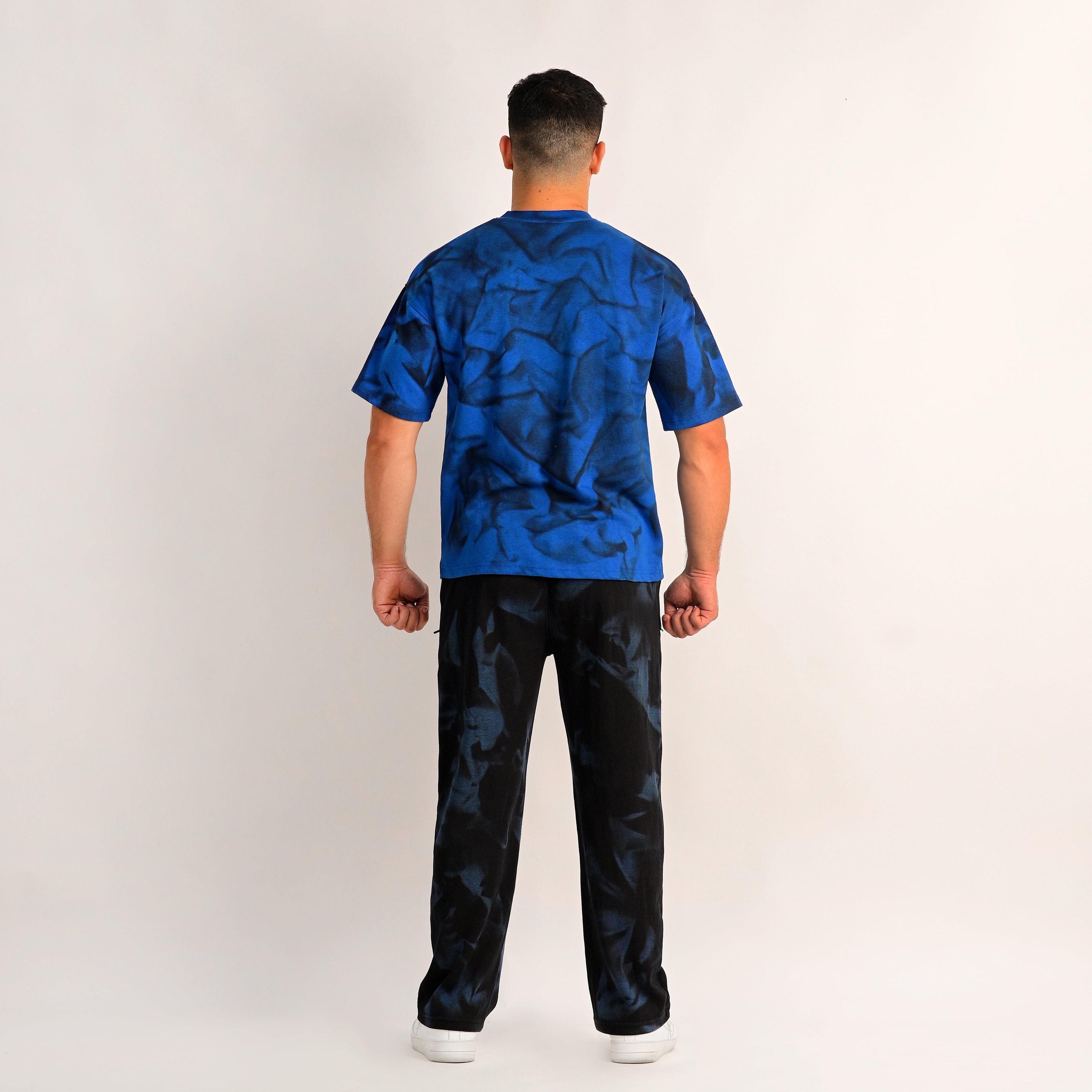 Person wearing a blue patterned shirt and black pants on a white background