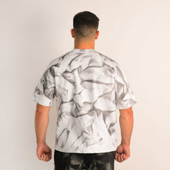 Person wearing a white t-shirt with black abstract pattern on a plain background